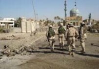 U.S. soldiers walk past the remains of one of the vehicles used in the attack (RFE/RL)