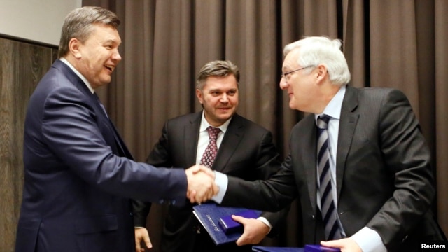 Eduard Stavytskyi, chairman of Ukraine's state geology and mineral resources service (center), watches as Ukrainian President Viktor Yanukovych (left) shakes hands with Peter Voser, CEO of Royal Dutch Shell in Davos, on January 24.