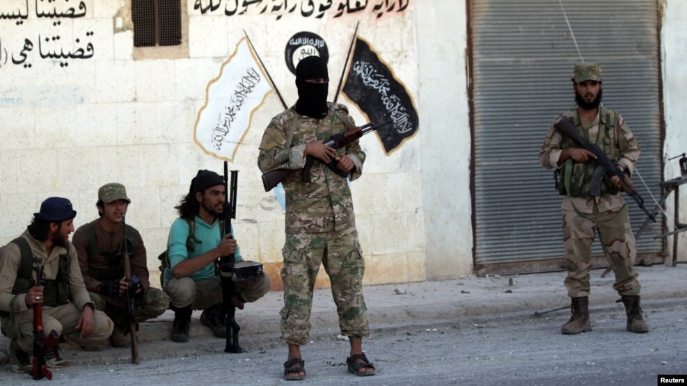 Syrian rebel fighters pose near Islamic State calligraphy and drawings in Dabiq after capturing the city on October 16.