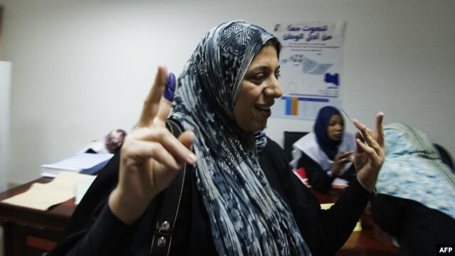 A Libyan woman raises her ink-stained finger after voting for Libya's General National Assembly at a polling station in Tripoli on July 7.