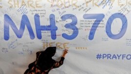 Malaysia -- A woman writes a message of support and hope for the passengers of the missing Malaysia Airlines MH370 on a banner at Kuala Lumpur International Airport March 12, 2014