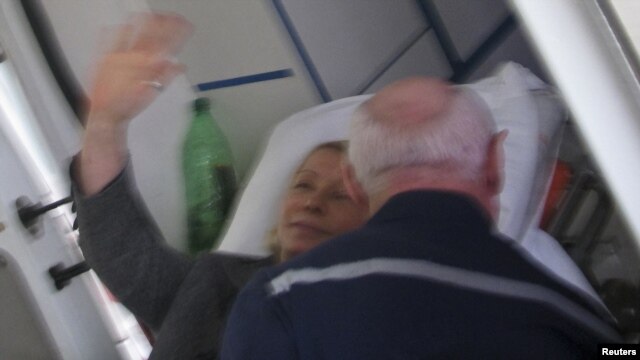 Yulia Tymoshenko waves from a stretcher as she is taken to an ambulance in Kharkiv on April 22.