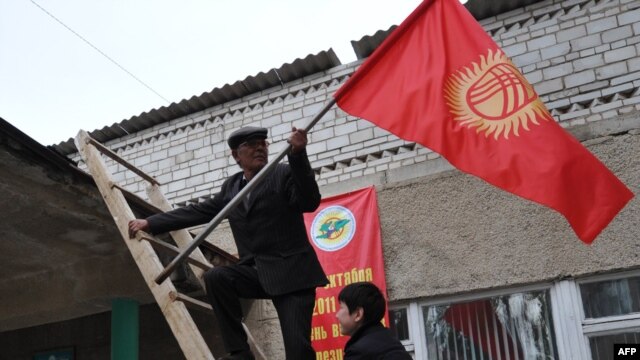 People fix national flags atop a local polling station in the Besh-Kungey village outside the Kyrgyz capital, Bishkek.