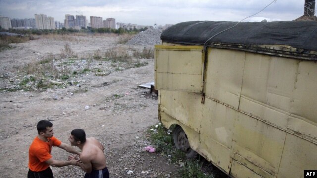 Two Tajik migrant workers relax after a day's work with the Moscow skyline behind them. (file photo)