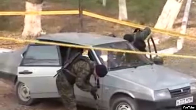A police investigator examines a car at the scene of the attack in Taraz.