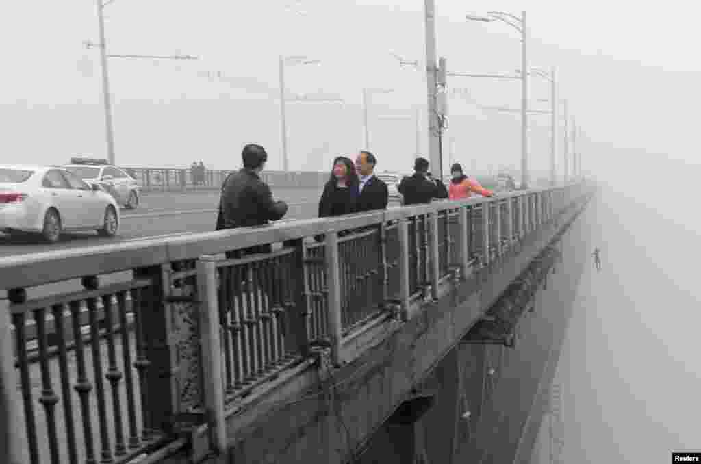 A person can be seen in the distance jumping off the Wuhan Yangtze River Bridge in China's Hubei Province. A young couple jumped into the Yangtze River from the bridge one after another in the haze on February 27. Police said the couple was still missing and is not believed to have survived. (Reuters/China Daily)