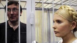 Former Interior Minister Yuriy Lutsenko (left, in defendant's cage) and Yulia Tymoshenko talk in a courtroom in Kyiv in May 2011.