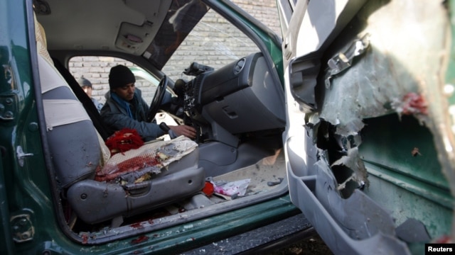 A police officer inspects the interior of the car the chief of police of Nimroz Province was in when it was hit by a roadside bomb that killed him.