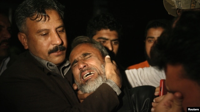 A man is comforted by his family as he mourns his brother, who was killed in the blast.