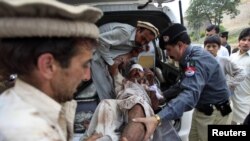 Relatives and police assist a man, who was injured in a suicide attack in a village of Kacha Pakha near Kohat on April 17.