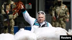 A woman waves orange ribbons of St. George, a symbol widely associated with pro-Russia protests, in front of the occupied town-administration building in the eastern Ukrainian town of Kostyantynivka late last month.