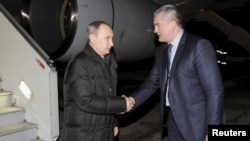 Russian President Vladimir Putin (left) shakes hands with Sergei Aksyonov, the de facto prime minister of the annexed Ukrainian peninsula, upon the former's arrival at Simferopol airport on December 2.