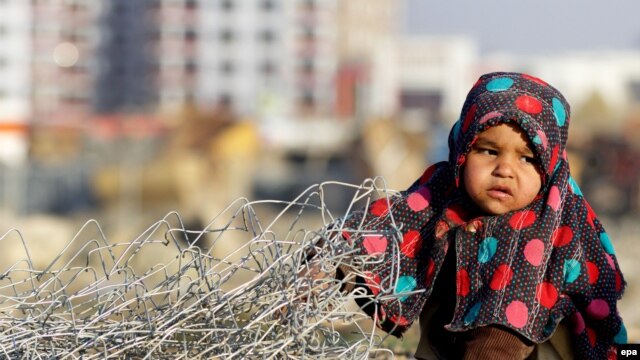 Афганская девочка-переселенка играет за пределами своего временного убежища для внутренне перемещенных лиц (ВПЛ) на окраине Кабула, Афганистан, 20 ноября 2015 года