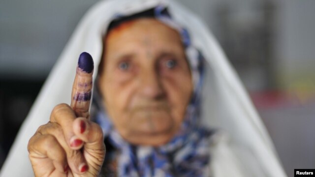 A woman shows her ink-stained finger after casting her vote during the National Assembly election in Benghazi.