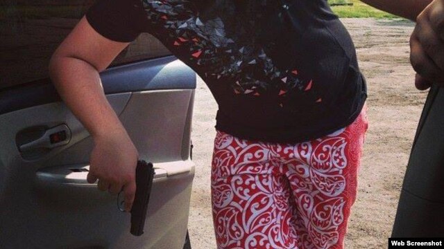 Подозреваемый в совершении ДТП подросток позирует у автомобиля с пистолетом в руках. 