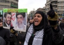 Iran -- An Iranian woman holds a poster of Iranian president Mahmoud Ahmadinejad (L) and Iranian supreme leader Ayatollah Ali Khamenei in Tehran, 3 Feb. 2006