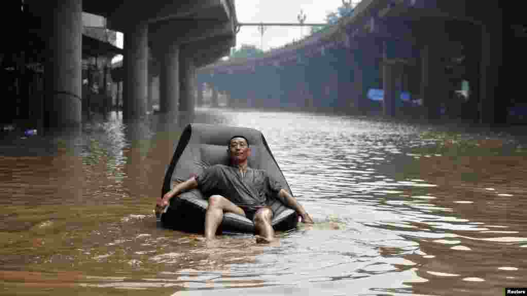 A man finds refuge on an inflatable sofa on a flooded street near the Yangtze River in China's Chongqing municipality on July 25. Torrential rain swept through 17 provincial areas, leaving nearly 100 people dead. (REUTERS)