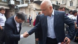 Oleksander Tymoshenko (right) shakes hands with an acquaintance in Kyiv in August.