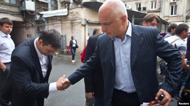 Oleksander Tymoshenko (right) shakes hands with an acquaintance in Kyiv in August.