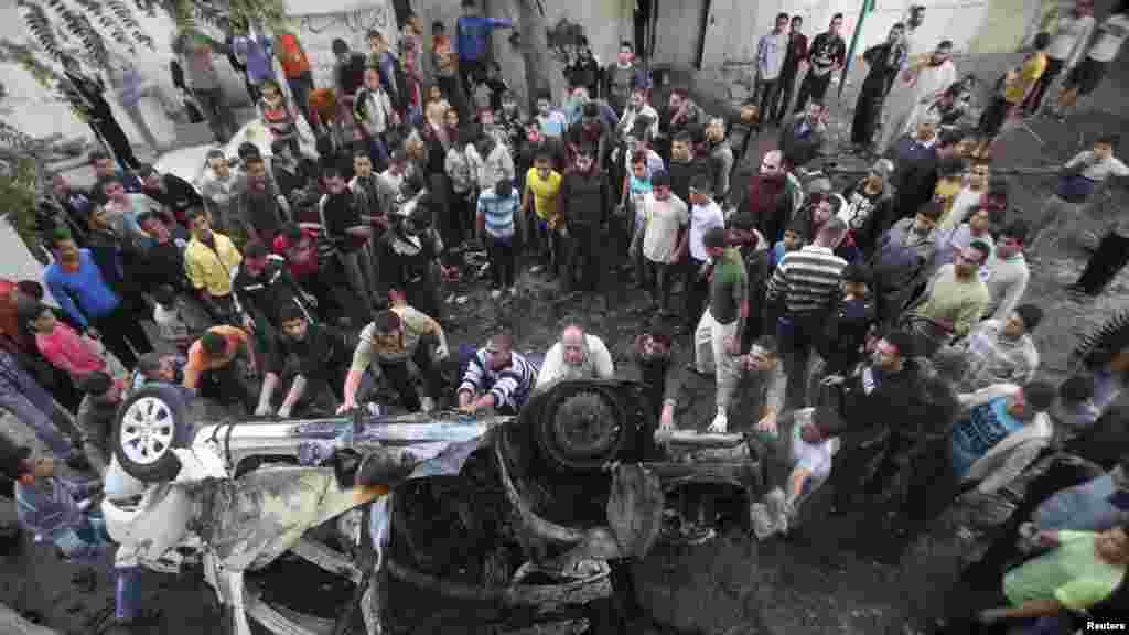 Palestinians gather around a destroyed car after an Israeli air strike in Gaza City. (Reuters/Ali Hassan)
