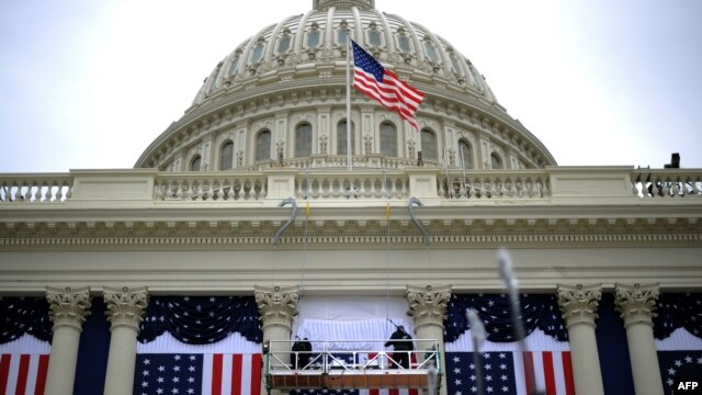 Workers adjust the U.S. flag on the Capitol as preparations continue for the second inauguration of President Barack Obama.