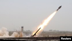 Members of Iraq's Shi'ite paramilitaries launch a rocket towards Islamic State militants on the outskirts of the city of Falluja, in the province of Anbar on July 12.