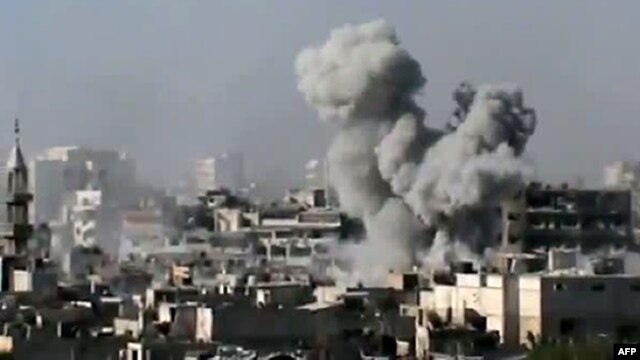 Syria -- A video grab shows smoke billowing from a building in the Jouret Sheikh neighbourhood of the restive central city of Homs, 01Jul2012