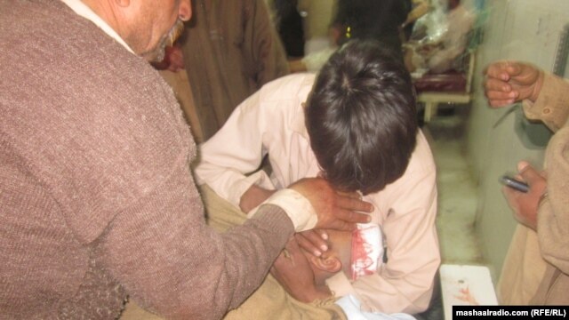 A man holds an injured relative after an explosion in Peshawar during a funeral ceremony killed at least 15.