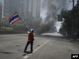An antigovernement protester waves a national flag during clashes in Bangkok on May 14.
