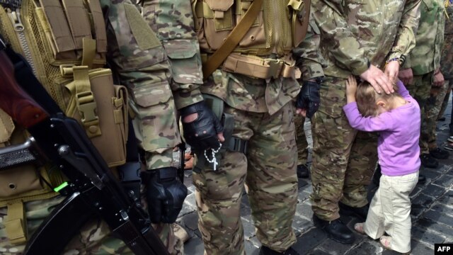 A child of a Sich special volunteer battalion member holds her father during an oath-taking and farewell ceremony in Kyiv on August 26.