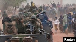 French troops aboard armored vehicles are greeted as they arrive in Timbuktu on January 28, after the Islamist rebels fled the city.