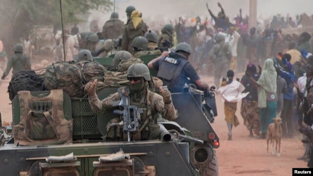 French troops aboard armored vehicles are greeted as they arrive in Timbuktu on January 28, after the Islamist rebels fled the city.