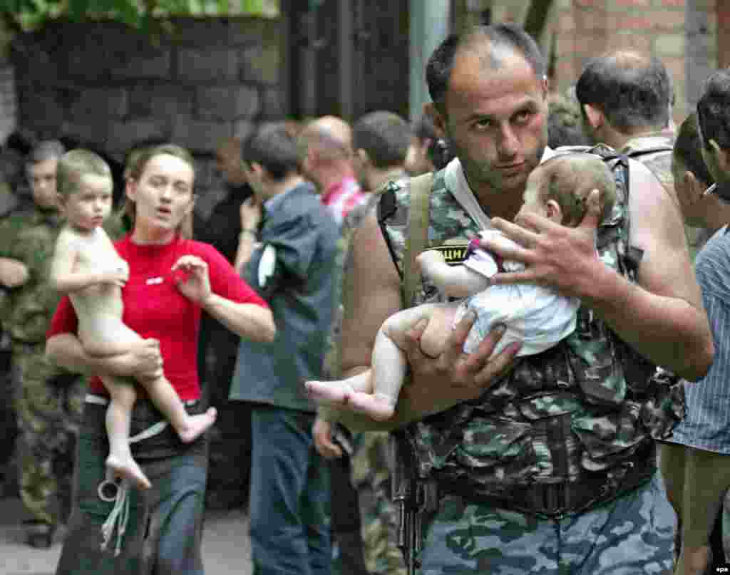 A soldier carries a baby after the release of 26 women and children on the second day of the crisis. Officials say the hostage takers started the massacre by setting off a bomb inside the school, but many in Beslan say the soldiers provoked the battle by firing a rocket-propelled grenade at the school, causing the roof to collapse and sparking a fierce blaze.