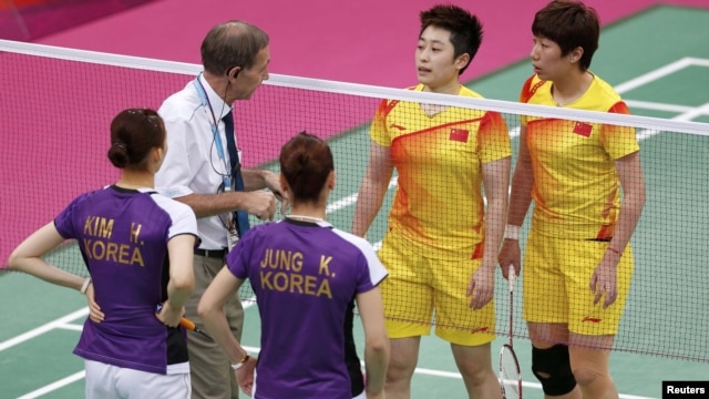 An official speaks to players from China and South Korea during their women's doubles badminton group match on July 31.