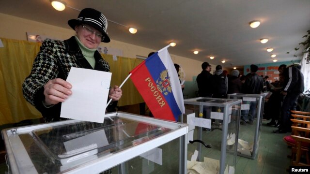 یک شهروند کریمه در حالی  که پرچم روسیه را درست دارد  در یک شعبه اخذ رای