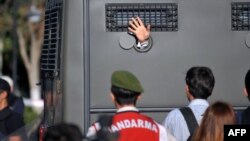 An Ergenekon prisoner being driven in a police armoured vehicle waves at protesters in August 2013 as police and gendarmerie block access to a courthouse in Silivri, near Istanbul.