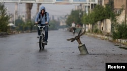 A resident rides his bicycle near what activists say is an exploded cluster-bomb shell in the Syrian town of Douma in November.