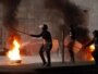 Egypt -- Riot police walk past a burning barricade during clashes in Cairo, 26Jan2011