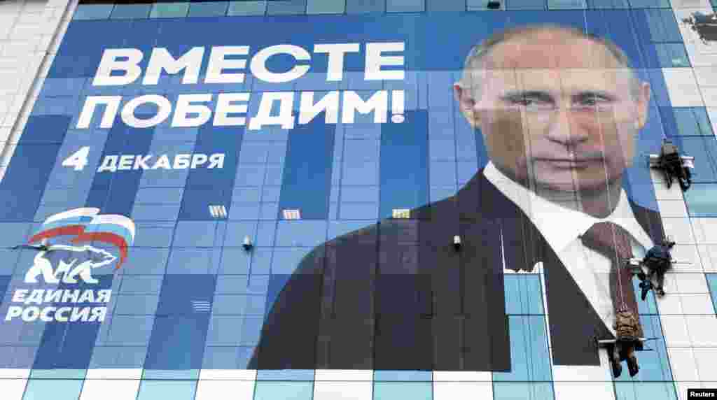 Workers attach an election poster featuring Prime Minister Vladimir Putin, appealing to people to vote for the United Russia political party, onto an office building in the southern city of Krasnodar late last year.