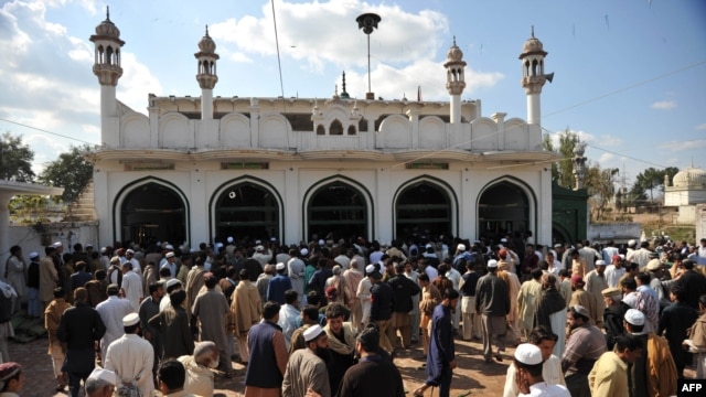 In this file photo, people gather outside a mosque in Nowshera after a bomb exploded there in March 2011.