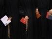 Iranian women hold prayer beads and registration cards as they wait to vote in Qom.