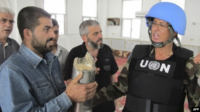 A Syrian resident shows a shell to a United Nations observer in the Talbisah area in Homs on June 11.