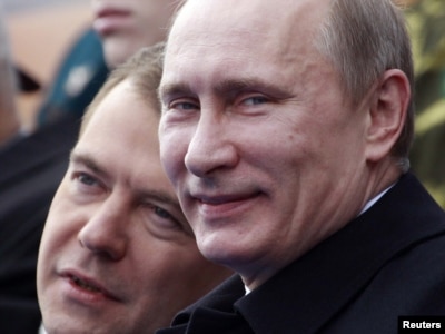 Russia -- President Dmitry Medvedev (L) and Prime Minister Vladimir Putin speak as they watch a military parade on Red Square on Victory Day in Moscow, 09May2011