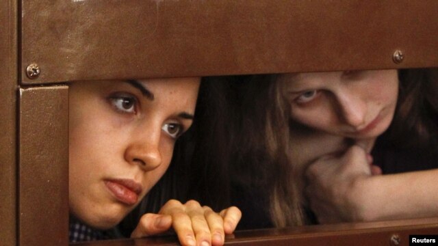 Nadezhda Tolokonnikova (left) and Maria Alyokhina, members of female punk band "Pussy Riot," look out from the defendant's cell in a courtroom in Moscow on July 30.