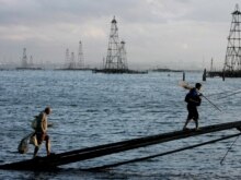 Azerbaijan - Two sailors walk in front of the oil derricks on the Caspian Sea near Baku, 07Oct2005
