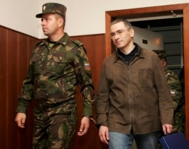 Полиция қызметкері Михаил Ходорковскийді (оң жақта) Мәскеу сотына әкеле жатыр. 20 қыркүйек 2005 жыл.