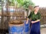Азербайджанка стоит возле бочек с водой.