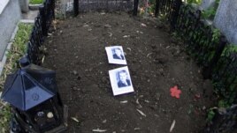 Two pictures of former communist dictator Nicolae Ceausescu lie on his grave after it was dug up to check whether it really contained his remains.