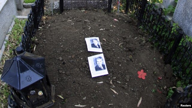 Two pictures of former communist dictator Nicolae Ceausescu lie on his grave after it was dug up to check whether it really contained his remains.