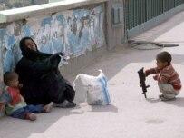 A woman begs in Baghdad while her child plays with a toy gun (file photo) (epa)